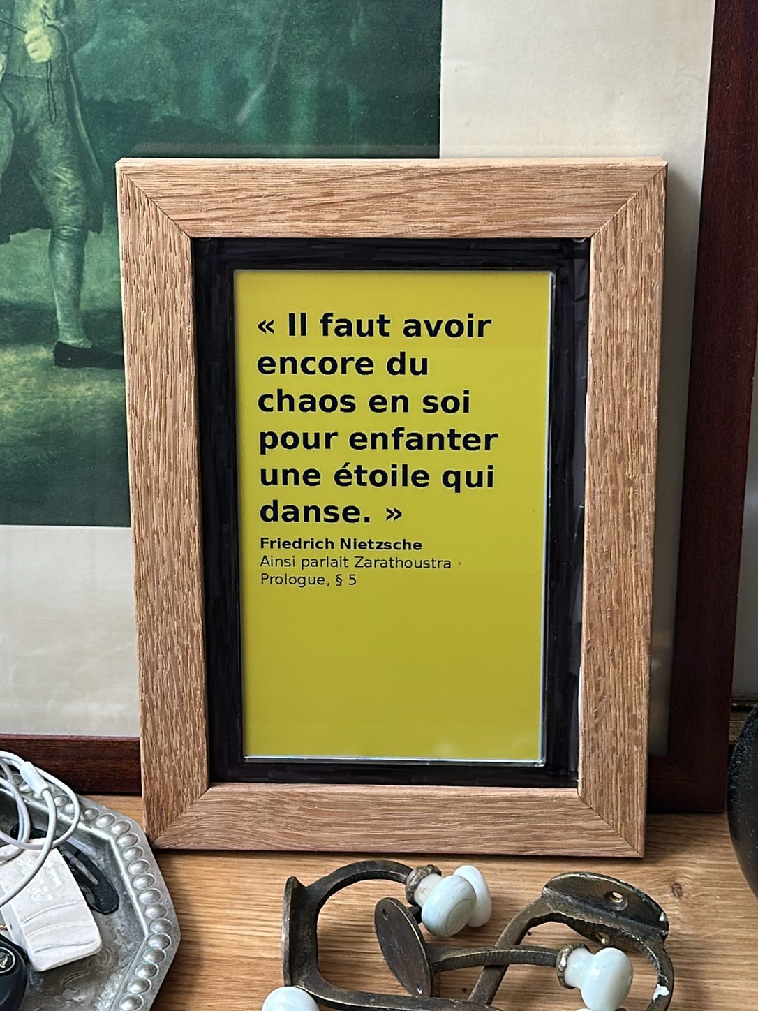 Cadre de chêne affichant en noir sur fond jaune une citation de Nietzsche tirée d’Ainsi parlait Zarathoustra.