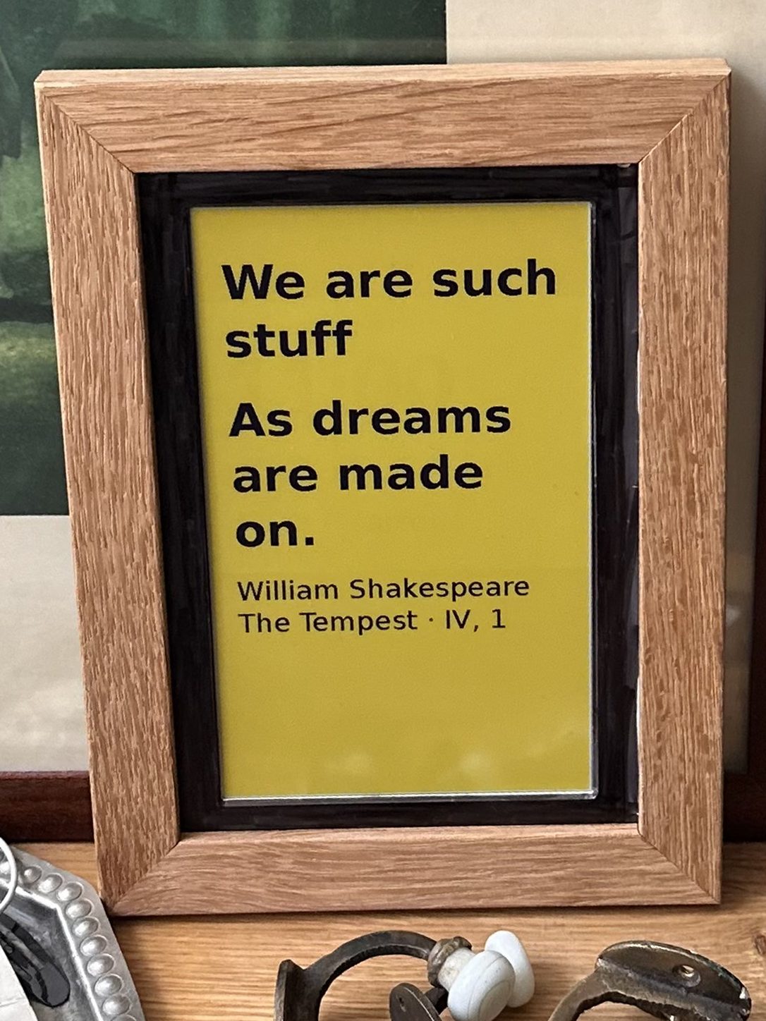 Cadre de chêne affichant en noir sur fond jaune « We are such stuff as dreams are made on », Shakespeare, La Tempête.
